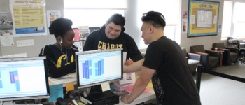 3 students looking at a computer