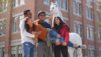 3 students holding another student while laughing